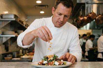 Chef de restaurant ajoutant des amandes effilées grillées sur un plat gastronomique en cuisine professionnelle