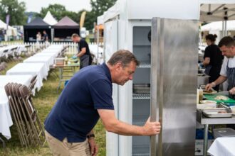 Homme inspectant un frigo lors d'un festival en plein air